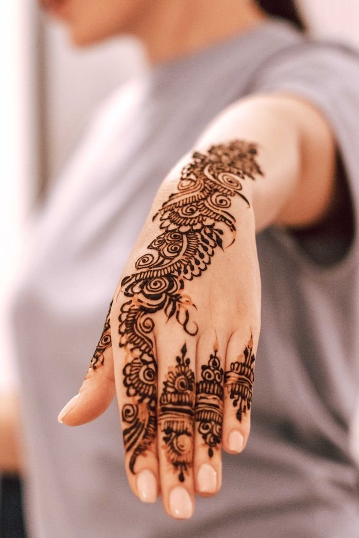 Close-up of a woman's hand with detailed henna art, showcasing cultural tradition and elegance.