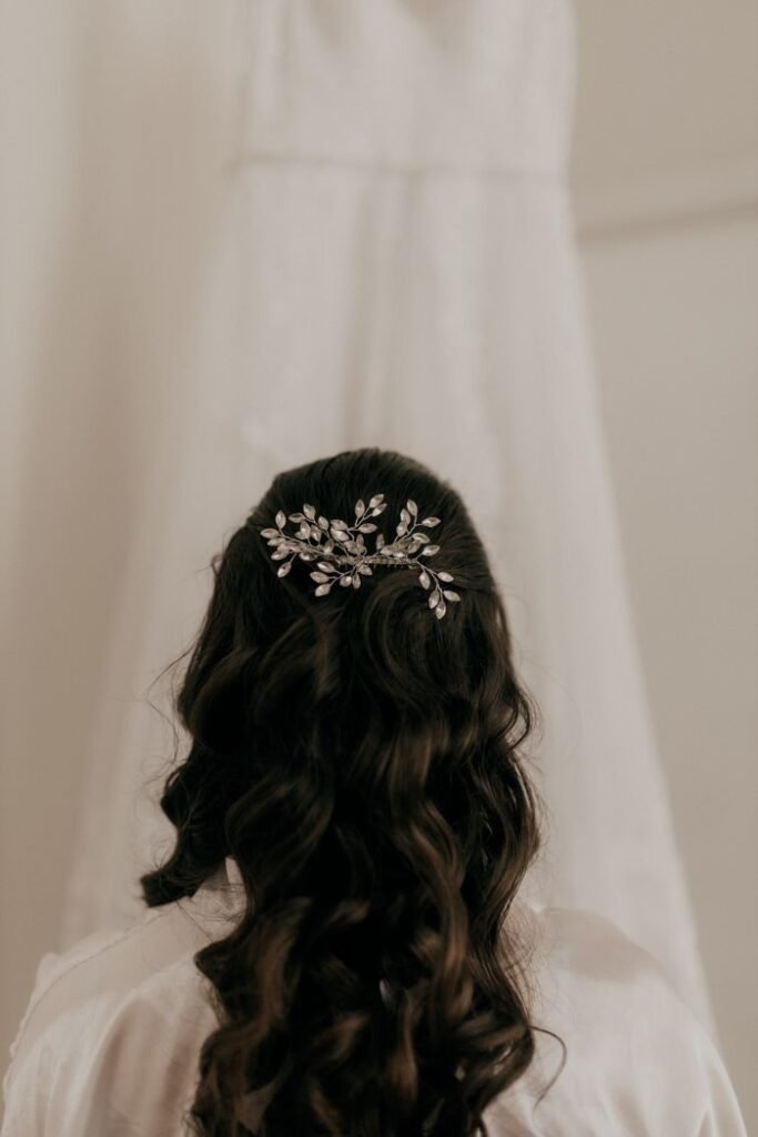 A bride's elegant hairstyle adorned with an ornamental hairpiece in soft focus.