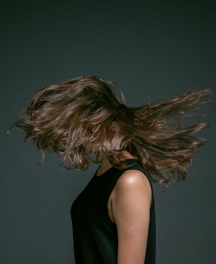 Artistic portrait of a woman with hair in motion, exuding energy and style.