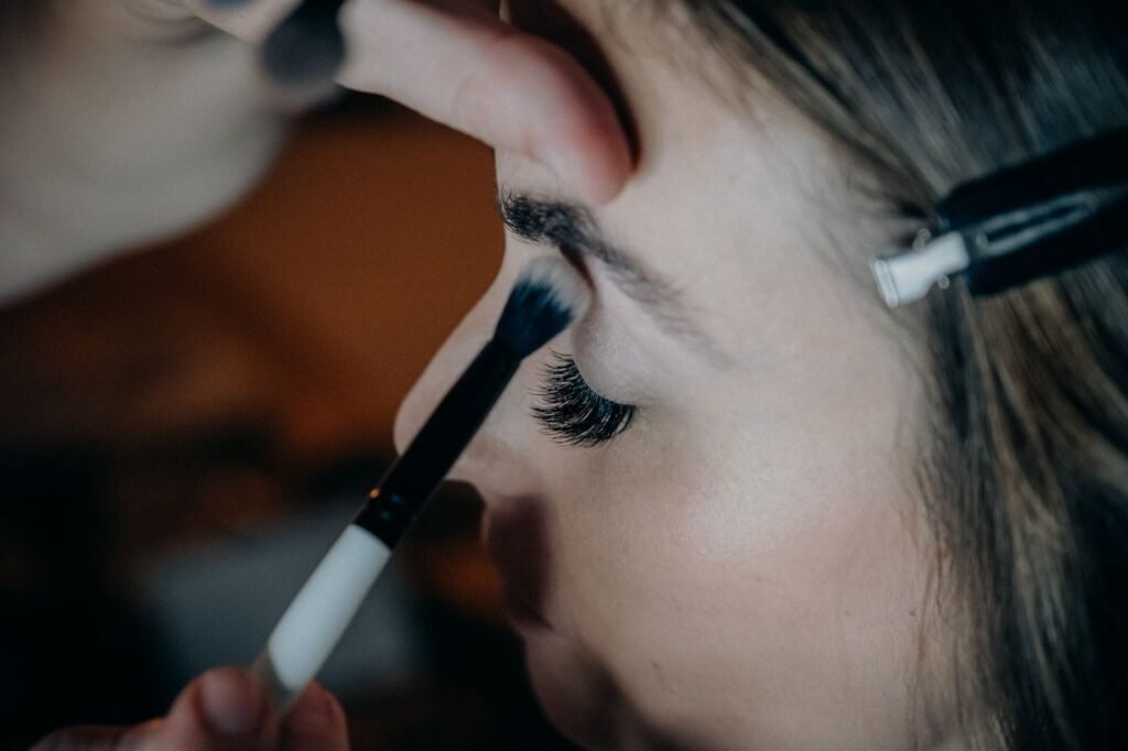 A detailed shot of a woman getting eye makeup applied with precision and artistry.